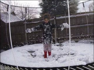 Child jumping on outdoor trampoline in winter
