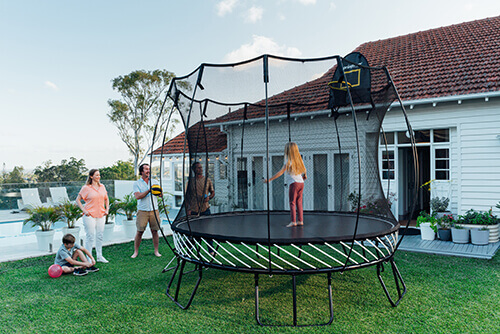 a girl inside a round trampoline and family in the backyard
