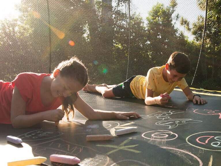 Two kids drawing in a trampoline