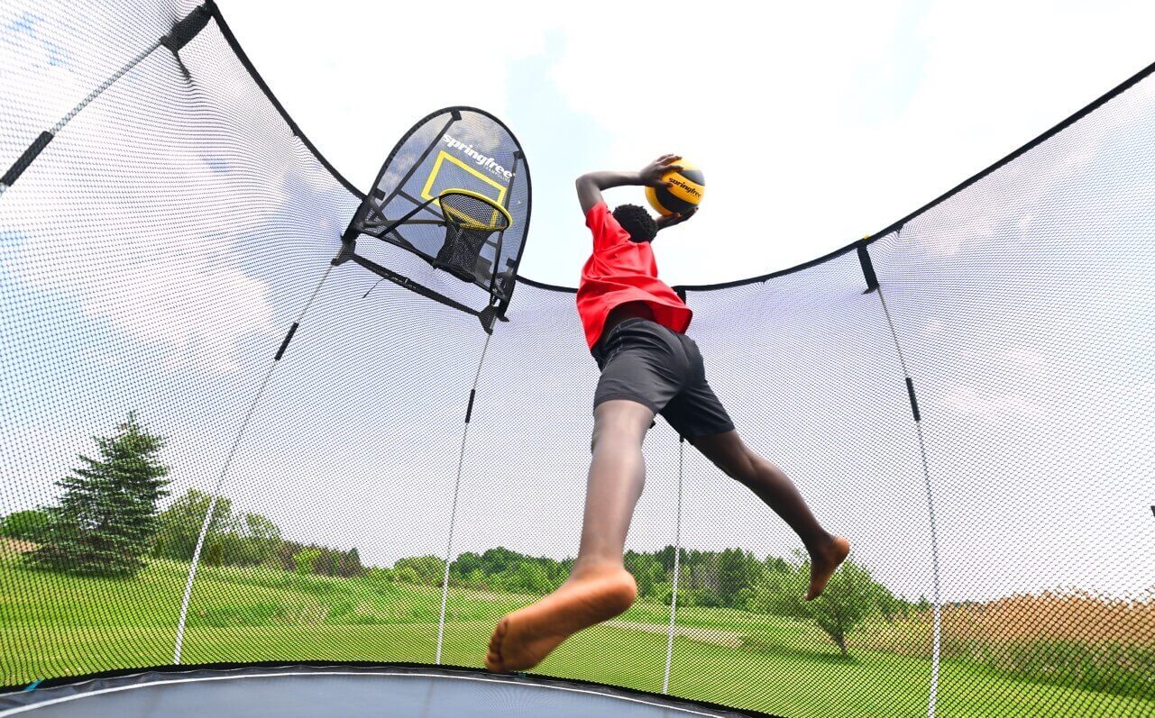 Little kid dunking on a Springfree Trampoline Basketball Hoop