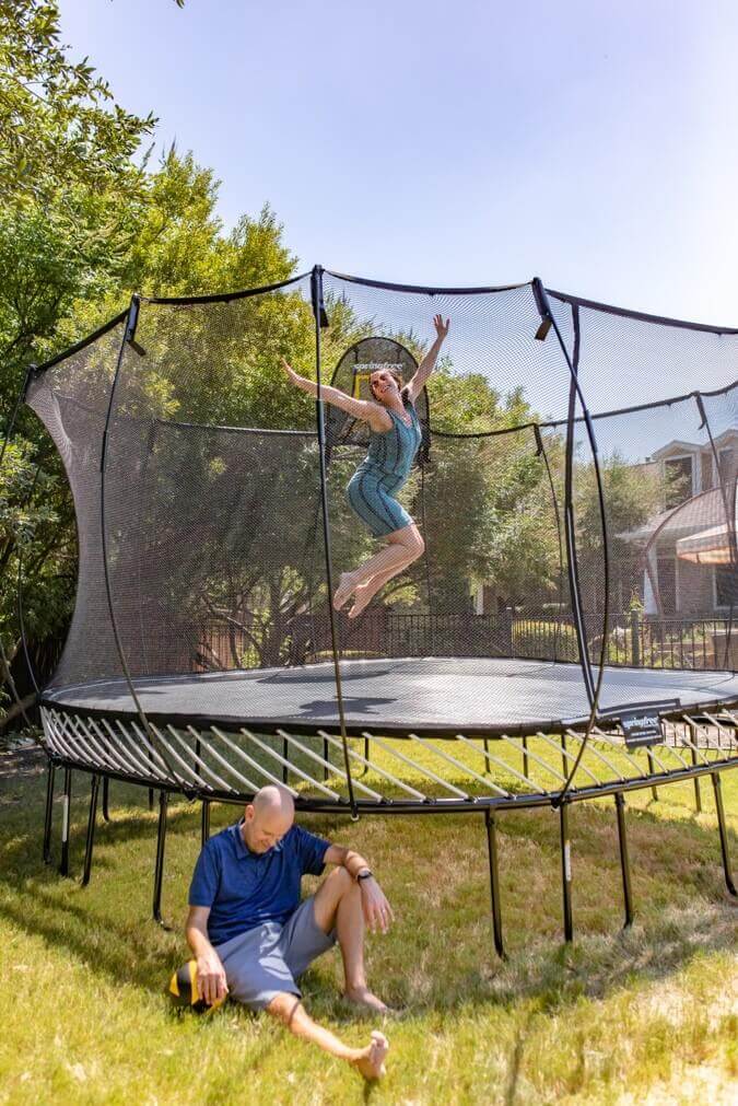 An adult jumping on a Springfree Trampoline.
