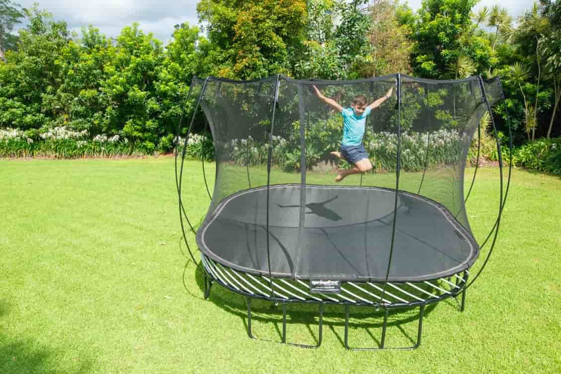 A kid jumping on a Springfree Large Square Trampoline.
