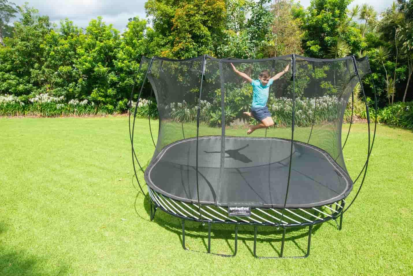 A boy jumping high in the air on a Springfree Trampoline.