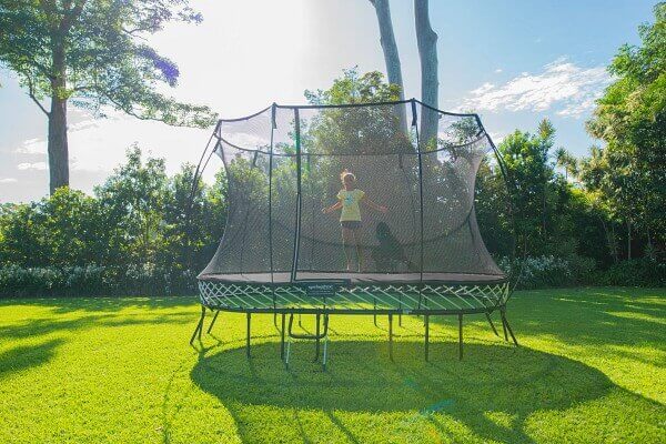 Little girl jumping on a Springfree Large Oval Trampoline in a yard