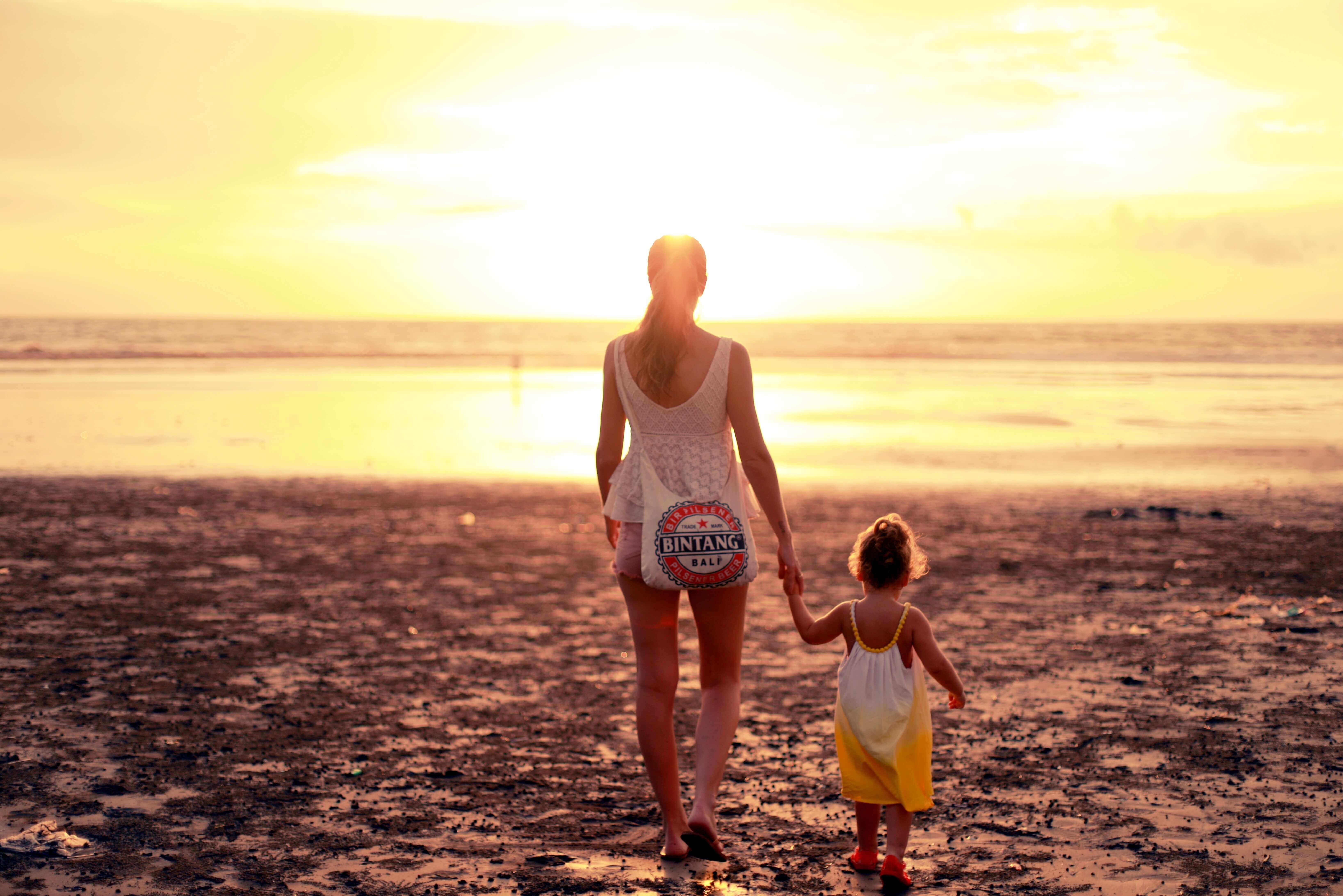 a mom and kid walking under the sunset