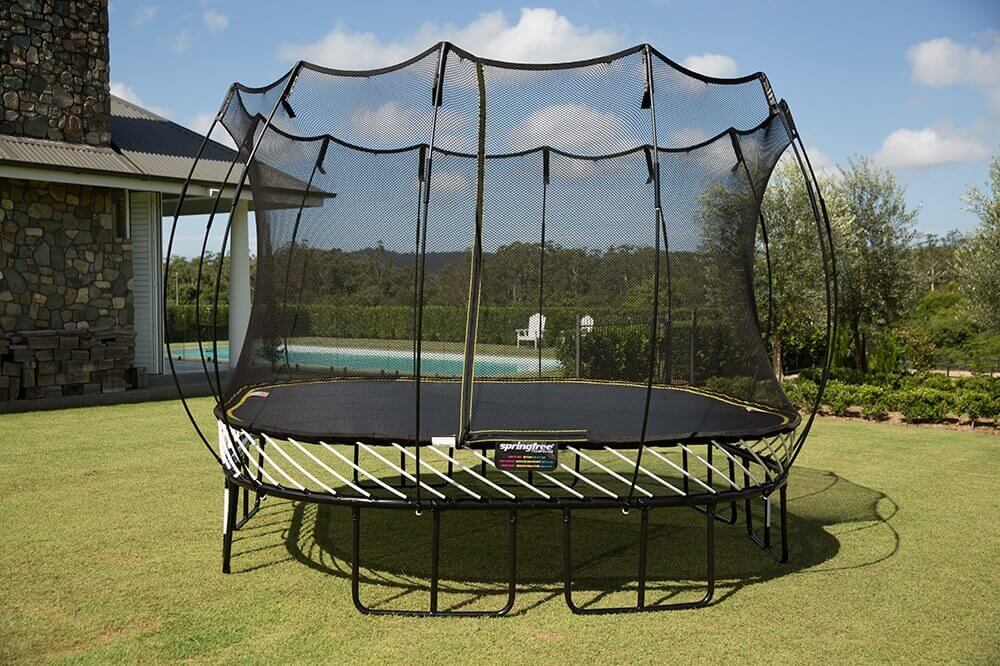 A Springfree Large Square Trampoline installed above the ground in a backyard