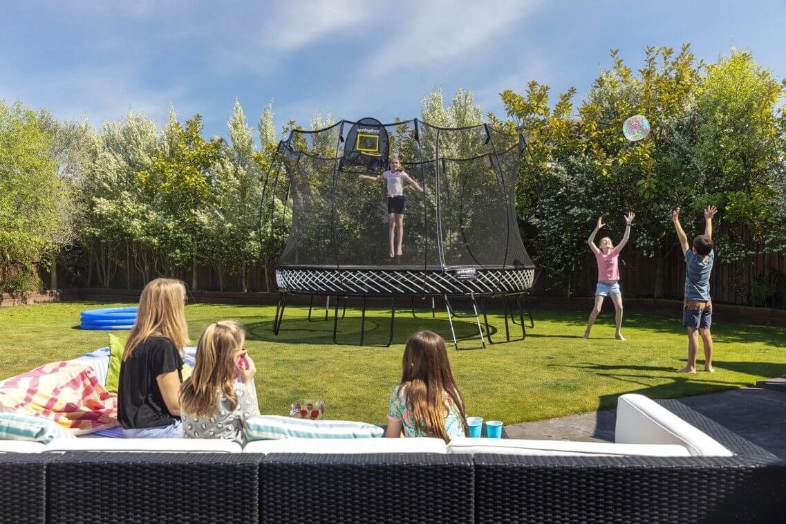 A kid jumping on a Springfree Trampoline while other kids play outside of it