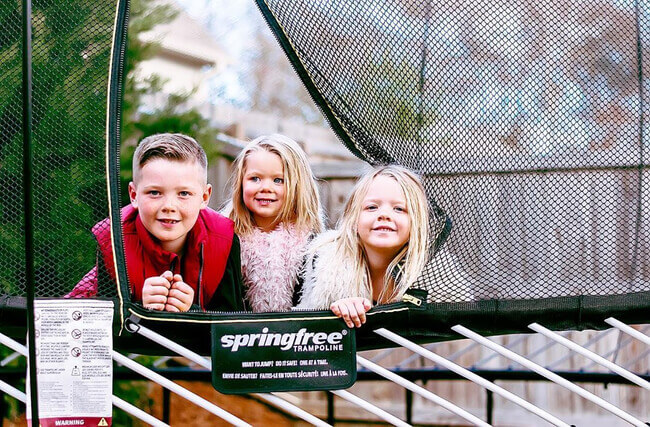 three kids smiling in a trampoline