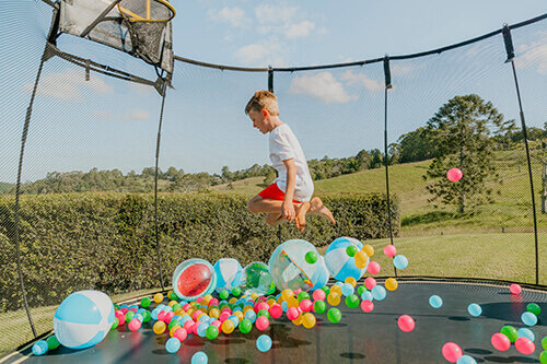 kid with balloons and balls in a trampoline