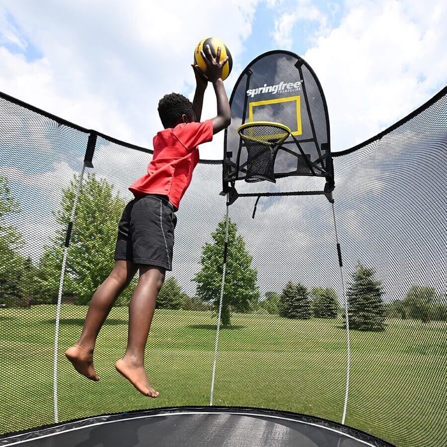 Boy dunking a basketball on a Springfree Trampoline