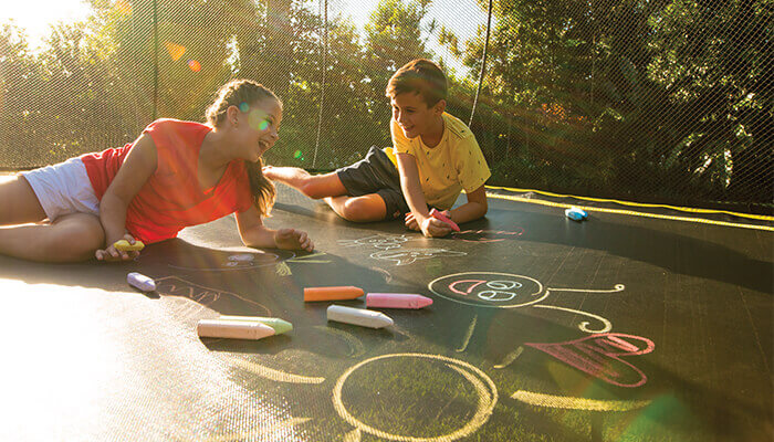 two kids drawing on a trampoline