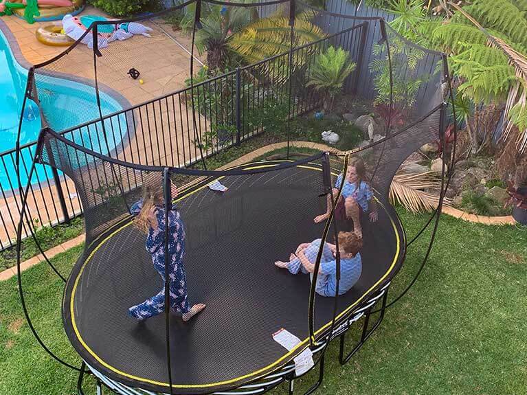 Happy kids playing on Springfree Trampoline in the backyard