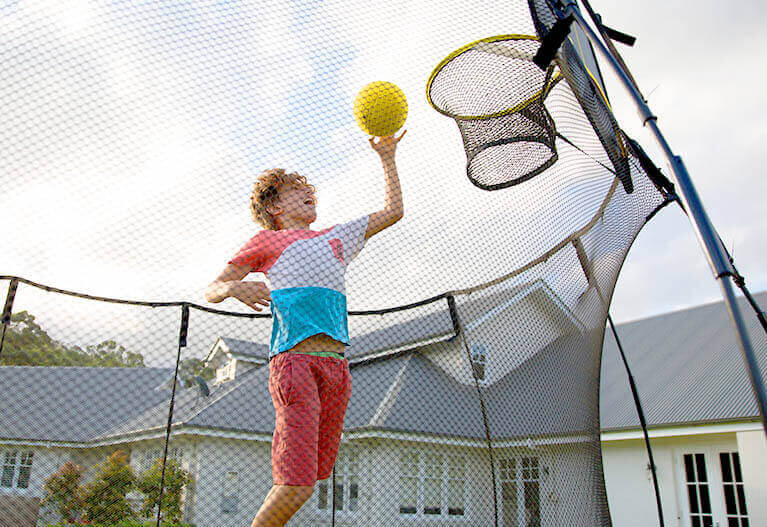 a boy doing slamdunk in a trampline