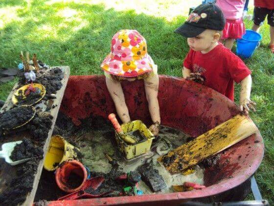kids playing in mud in wheelborrow